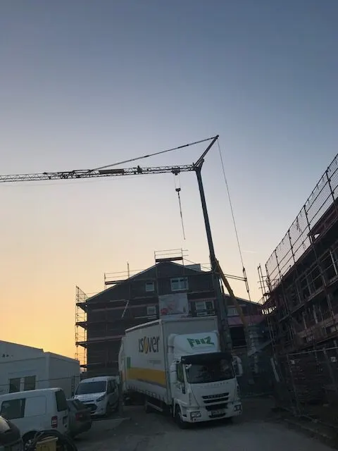 FHZ-Lkw am Abend vor einem eingerüsteten Gebäude mit Baukran
