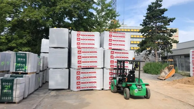 Hoch gestapelte Rockwool-Pakete auf dem Hof, daneben ein Stapler