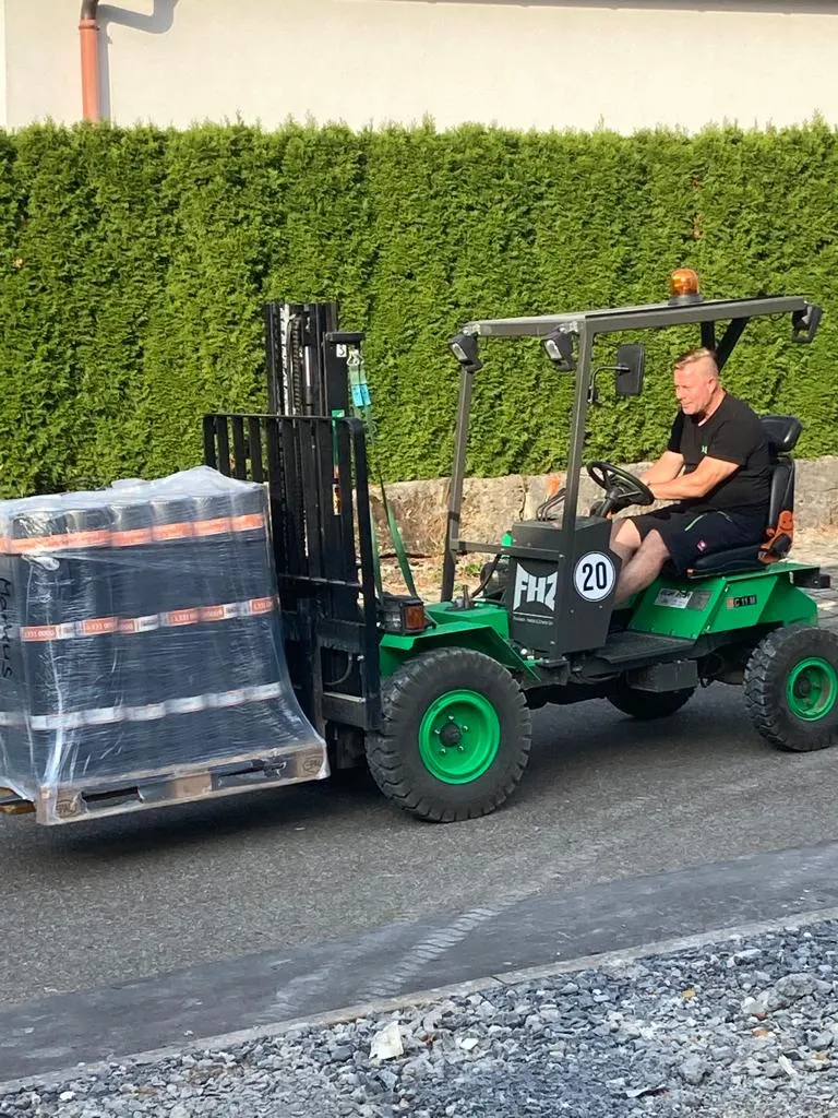 Grüner FHZ-Mitnahmestapler transportiert eine folierte Palette