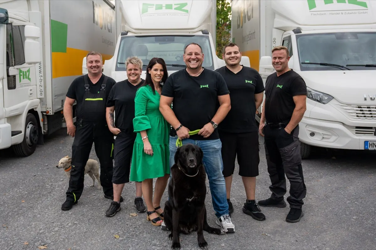 Das Team der FHZ Flachdach-Handel & Zubehör GmbH vor den eigenen Lieferfahrzeugen